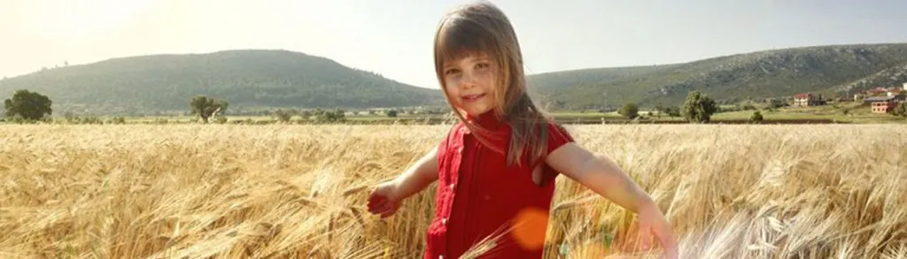 A girl running through a field of ripe wheat